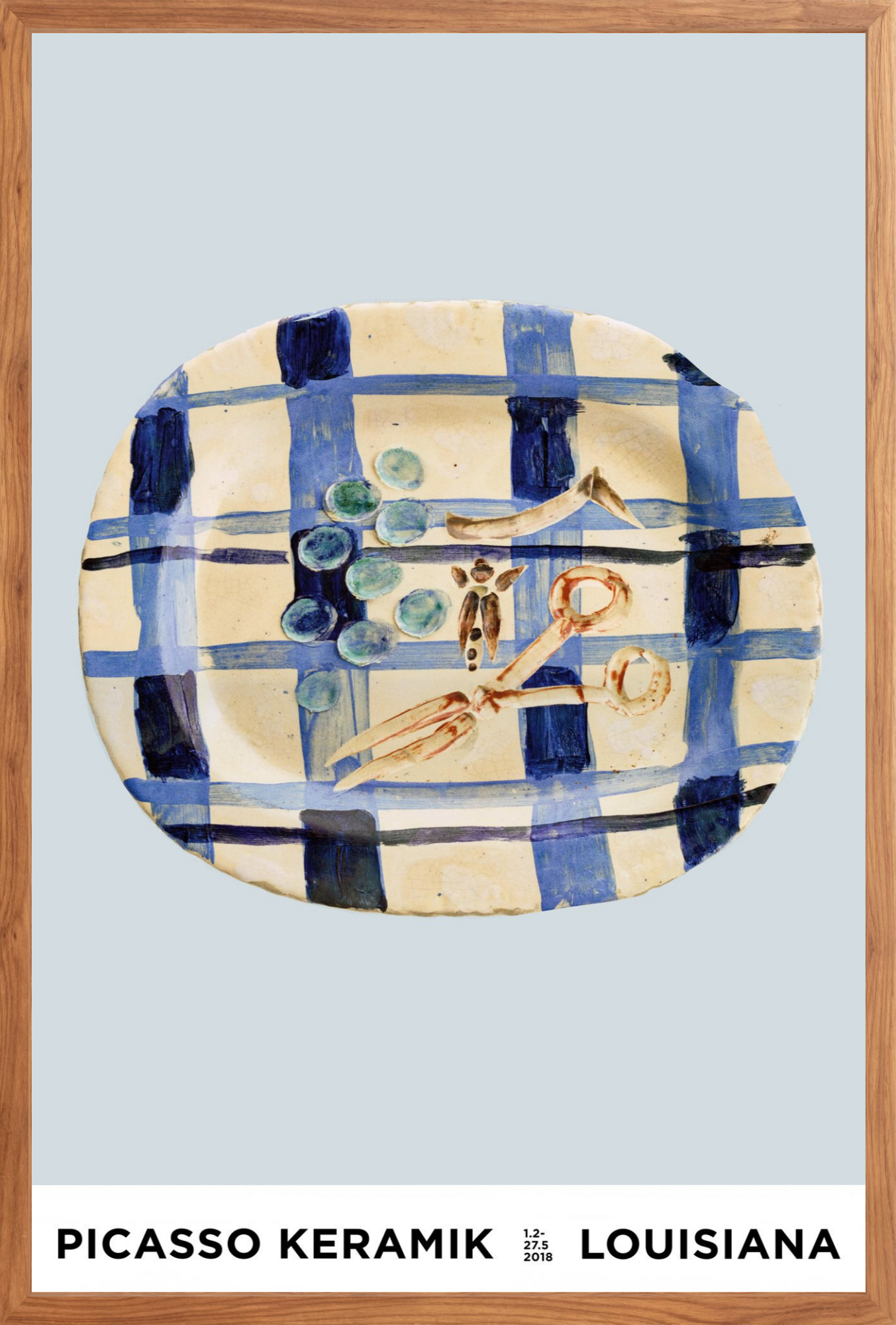 A framed art print featuring a Picasso ceramic plate with a blue and cream plaid pattern and abstract painted details, with text at the bottom reading 'PICASSO KERAMIK LOUISIANA'.