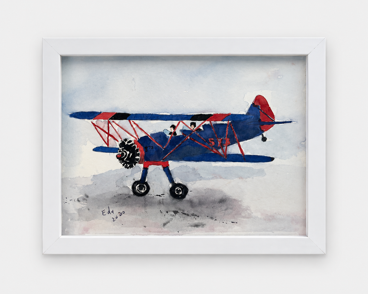 Watercolor painting of a red and blue vintage biplane, signed and dated 2000, in a white wood frame