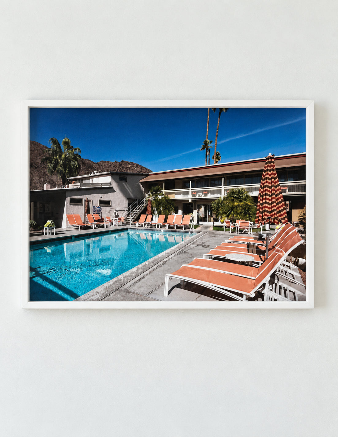 Photograph of a mid-century Palm Springs hotel pool with orange loungers, in a white frame